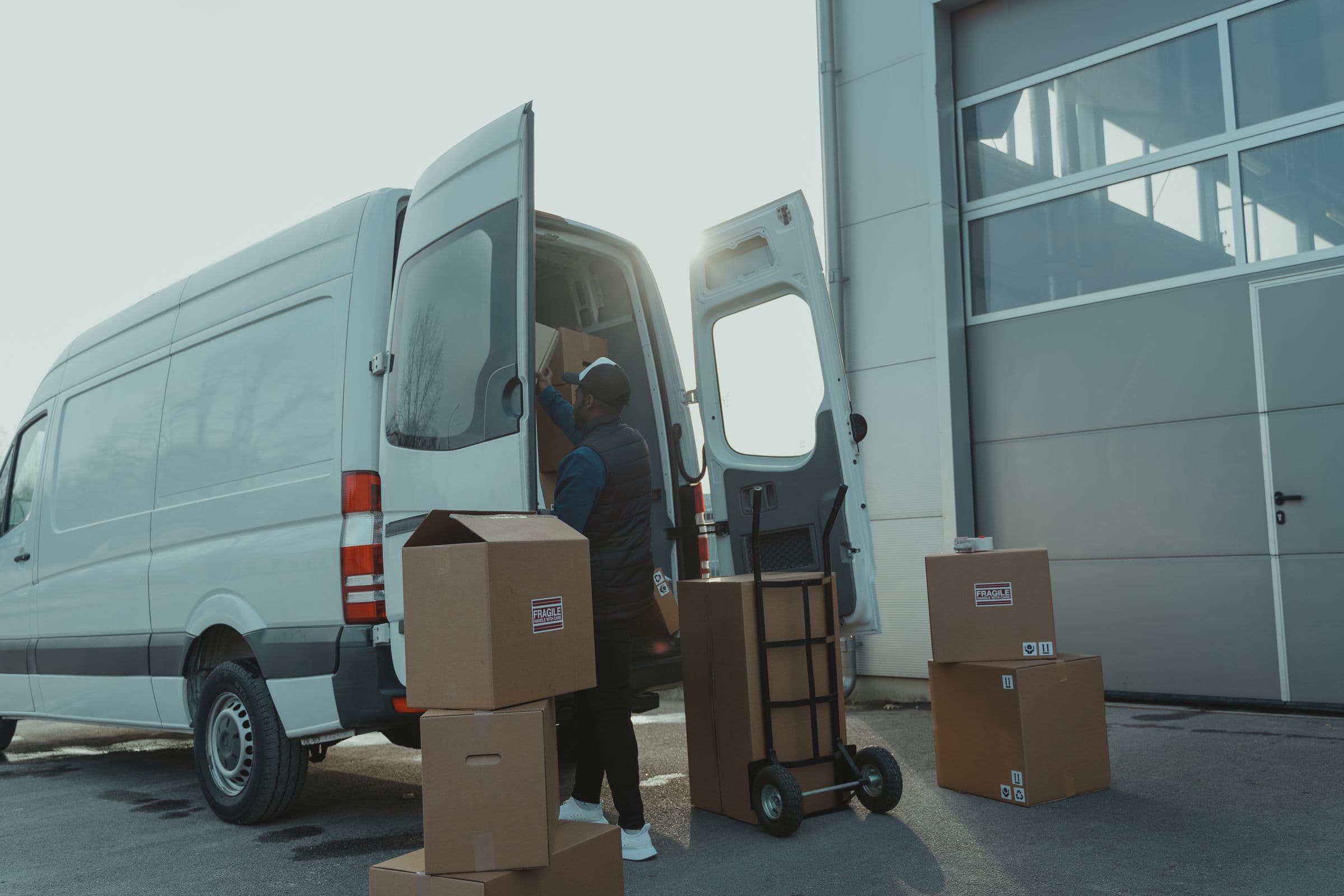 Courier loading urgent consignments into a dedicated delivery van outside a warehouse